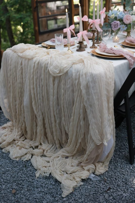 Romantic tablescape with gauze runner and pink ribbon candles